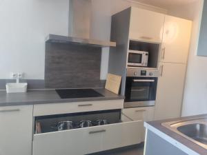 een keuken met witte kasten en een kookplaat oven bij 150 m de la cure thermale emplacement idéal iter Cadarache in Gréoux-les-Bains +9 foto's