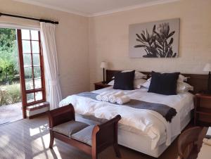 a bedroom with a large bed and a chair at Le Petit Vignoble in Cape Town
