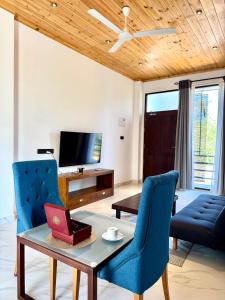 a living room with blue chairs and a table and a tv at Clear Point Studio in Dickwella