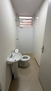 a white bathroom with a toilet and a sink at Pensão Feminina Independência in Piracicaba