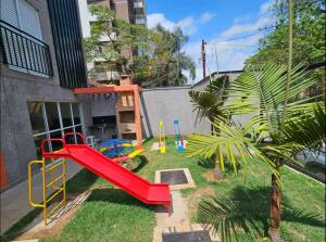 a playground with a red slide in a yard at Cobertura Vl Sônia Morumbi in Sao Paulo