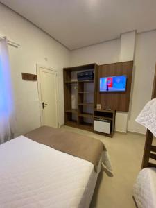 a bedroom with a bed and a flat screen tv at Pousada Natália in Torres