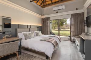a bedroom with a bed and a desk and a window at Mokuti Etosha in Namutoni +37 photos