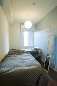 a bedroom with a bed and a mirror and a window at Stadt Leben東北ゲートウェイI in Sendai