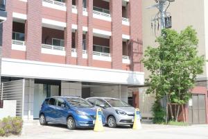 two cars parked in a parking lot in front of a building at Stadt Leben東北ゲートウェイI in Sendai