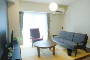 a living room with a blue couch and a table at Stadt Leben東北ゲートウェイI in Sendai