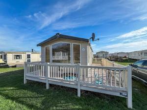 a small dog house with a white fence at Lovely Caravan With Spacious Decking At North Denes In Suffolk, Ref 40134Nd in Lowestoft