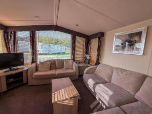 a living room with a couch and a tv at Lovely Caravan With Spacious Decking At North Denes In Suffolk, Ref 40134Nd in Lowestoft