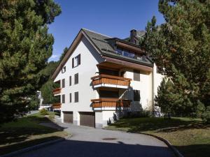 a white building with wooden balconies on a street at Apartment Chesa Nair 9D by Interhome in Surlej