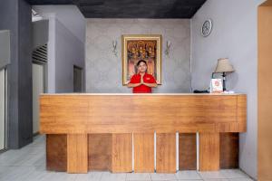 a woman standing behind a wooden counter in a room at Hotel O Near Tugu Yogyakarta 1 formerly Crown Residence in Jetis
