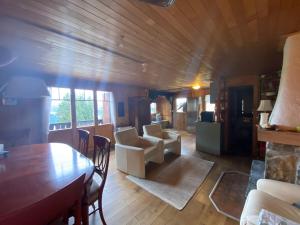 a living room with a wooden ceiling and a table and chairs at Chalet La Marmotte 1800m in Ollon