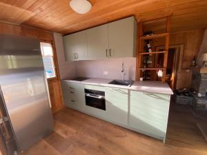 a kitchen with white cabinets and a stainless steel refrigerator at Chalet La Marmotte 1800m in Ollon +23 photos