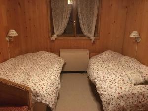 a bedroom with two beds and a window at Chalet La Marmotte 1800m in Ollon