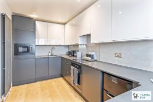 Una cocina con gabinetes blancos y electrodomésticos de acero inoxidable. en Coastal Breeze Retreat, en Swanage