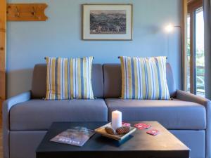 eine blaue Couch mit Kissen und eine Kerze auf dem Tisch in der Unterkunft Studio Le Bristol A25-31 by Interhome in Villars-sur-Ollon + 23 Fotos