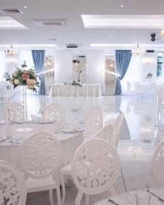 a white dining room with a table and chairs at Hotel Rivera in Dobrich