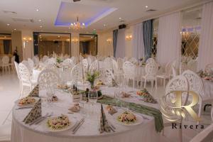 a banquet hall with white chairs and a table with flowers at Hotel Rivera in Dobrich +8 photos