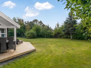 a backyard with a wooden deck and a lawn at Holiday Home Mechthild - 2-7km from the sea by Interhome in Saltum +18 photos