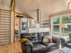 a living room with a leather couch and a kitchen at Holiday Home Mechthild - 2-7km from the sea by Interhome in Saltum