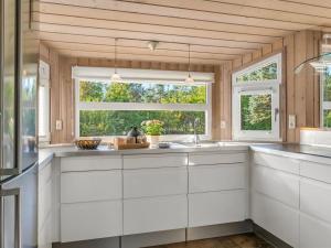 a kitchen with white cabinets and a large window at Holiday Home Mechthild - 2-7km from the sea by Interhome in Saltum