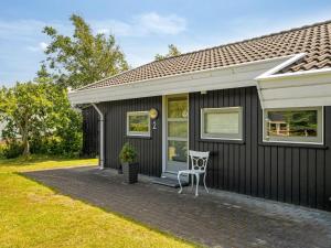 a black house with a chair on a patio at Holiday Home Gita - 2-2km from the sea by Interhome in Saltum