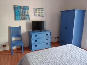 a bedroom with a blue dresser and a tv and a blue chair at Holiday House Ginevra in Formia