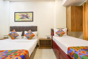 a room with two beds and a night stand in it at FabHotel Aksa Inn in Mumbai