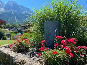 a garden with pink flowers and a plant in a pot at Ferienhaus Alpenperle in Grainau
