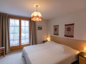 ein Schlafzimmer mit einem weißen Bett und einem großen Fenster in der Unterkunft Apartment Chaperon Rouge B5 by Interhome in Chesières