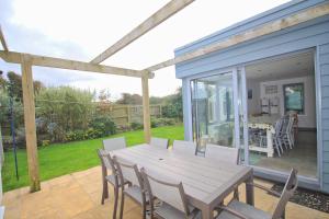 a patio with a wooden table and chairs on a deck at MODERN HOLIDAY HOME central St Merryn in Saint Merryn