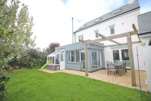 a house with a patio with a table and chairs at MODERN HOLIDAY HOME central St Merryn in Saint Merryn