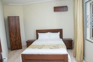 a bedroom with a bed with white sheets and wooden furniture at Yaoundé in Yaoundé +1 photo