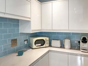 a kitchen with white cabinets and a microwave at The Room Next Door in Flemingston