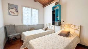 a room with two beds and a chair and a window at Jolie villa de plain-pied avec jardin et parking in La Couarde-sur-Mer