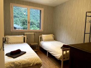 two beds in a small room with a window at Mountain view 3-bedroom Pyrenees apartment in Saint-Béat