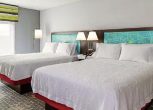 マニトワックにあるHampton Inn Manitowocの白いシーツが敷かれたホテルの部屋にベッドが2つある