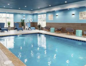 マニトワックにあるHampton Inn Manitowocのホテルのロビーにある大きなスイミングプール(椅子、テーブル付)