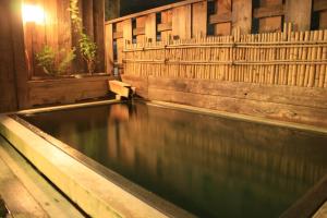 a pool of water in a room with a wooden wall at Kashiwaya in Chikuma