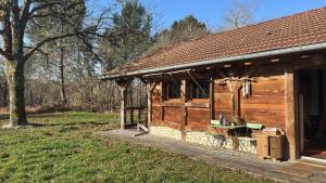 a wooden cabin with a porch in a field at Tranquil Barn dans le foret in Sabres
