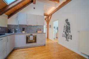 a kitchen with white cabinets and a wooden floor at LUXOMES - Tropical & Streetart Style - Old Town Apartments - Central Ingolstadt in Ingolstadt