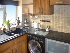 a kitchen with a washing machine and a sink at Mariners Cottage in Dawlish