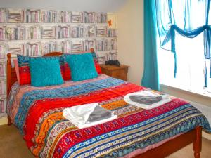 a bedroom with a bed with towels and books at Mariners Cottage in Dawlish
