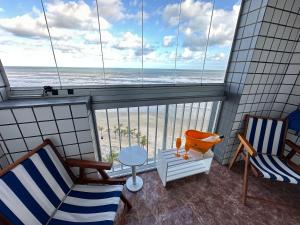 d'un balcon avec deux chaises et une vue sur la plage. dans l'établissement Vista deslumbrante e elegância frente mar!, à Vila Balneária