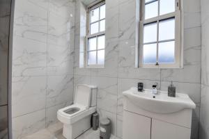 a white bathroom with a toilet and a sink at Cosy Wigan Apartment with Sunny Views in Wigan