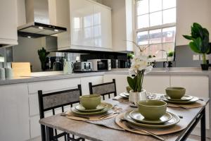 a kitchen with a table with plates and bowls on it at Cosy Wigan Apartment with Sunny Views in Wigan