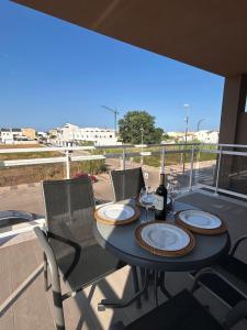 a table on a balcony with a bottle of wine at Oliva Sol Apartment in Oliva