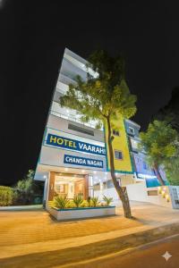 a hotel with a tree in front of a building at Hotel Vaarahi Chanda Nagar, Near Hitech City in Hyderabad