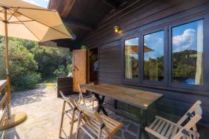 a wooden table and chairs on a patio with an umbrella at Casette nel Parco in Portoferraio +13 photos