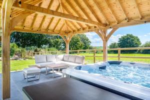 a hot tub in a pavilion with a couch and a table at 4 Bed in Woolfardisworthy oc-s32421 in Woolfardisworthy