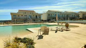 a swimming pool with chairs in front of a building at Olimpia Holiday in Marzamemi